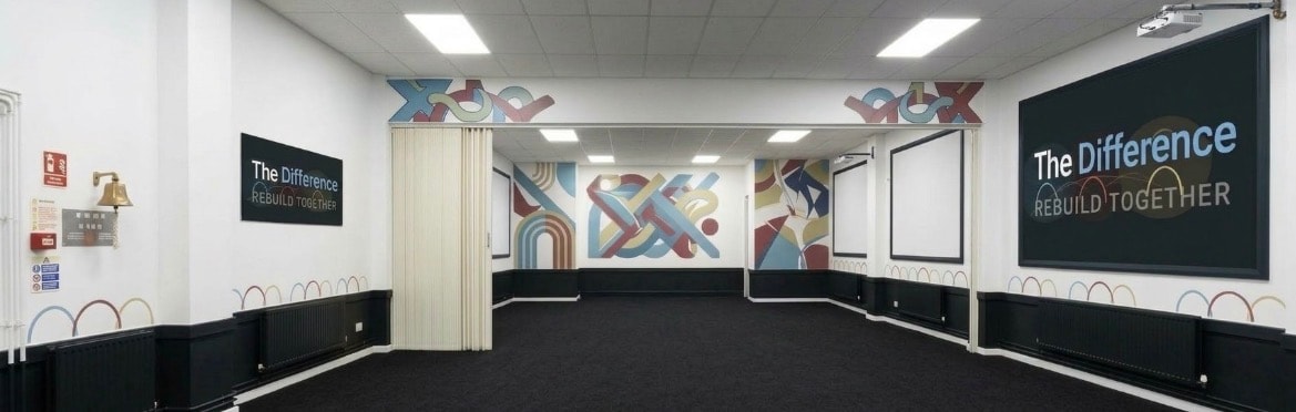 The Difference venue interior — a spacious, branded room with colourful murals, projection screens, and professional facilities